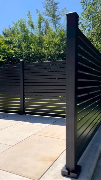 Modern Horizontal Slat Metal Fence with Paved Patio in Backyard Setting